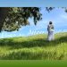 A woman in a white dress stands on a grassy hillside beneath tall pine trees, gazing at the open sky. The text overlay reads, “How to Attain Self-Realization?”