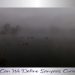 A mist-covered lake at dawn with faint silhouettes of trees in the background and a few ducks gliding quietly across the water.