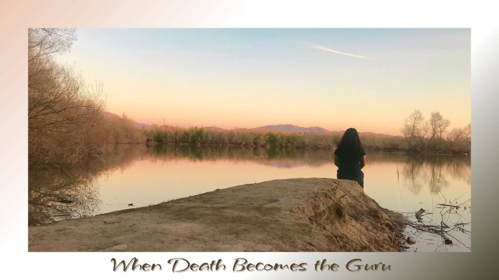 “Woman sitting silently by a calm river at sunset, reflecting on life as death becomes the greatest teacher.”