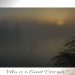 The sun rises faintly through a heavy mist over calm waters, with silhouetted trees and tall grasses framing the scene in quiet reverence.