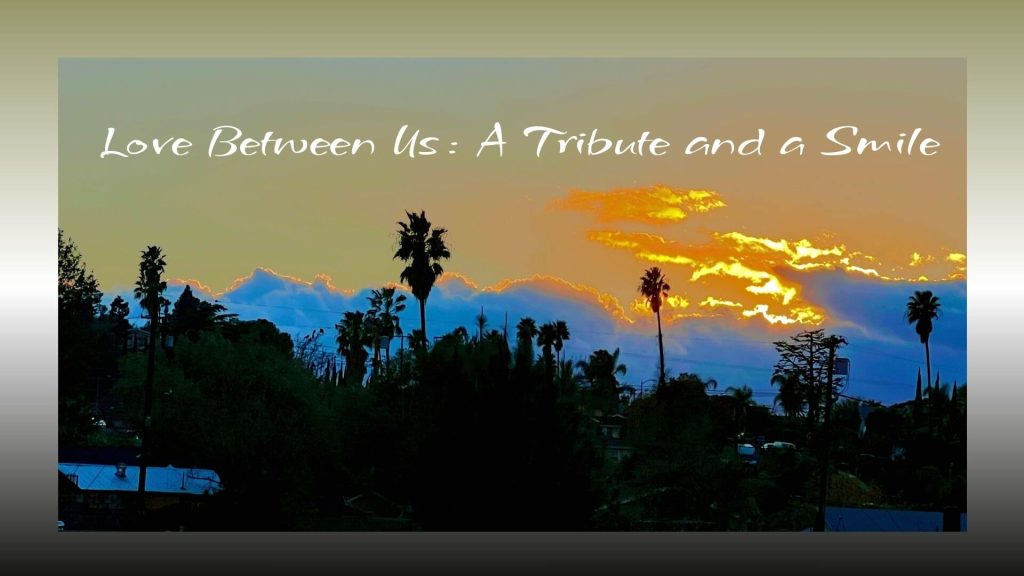 Sunset sky with golden clouds glowing above silhouettes of palm trees and rooftops. The text overlay reads, “Love Between Us: A Tribute and a Smile.”